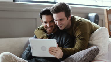 Young male couple looking at digital tablet
