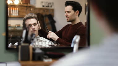 Young male having haircut in traditional barber shop