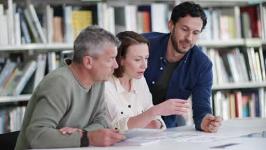Teacher helping mature students in library
