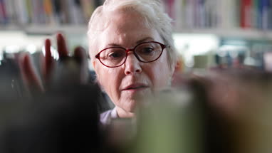 Senior female looking for a book in library