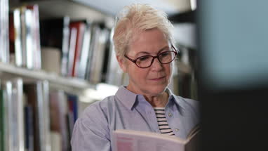 Senior female reading a book in library