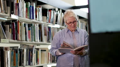 Senior female reading a book in library