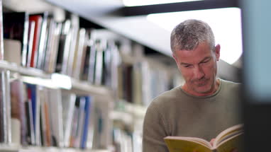 Senior Male looking for a book in library