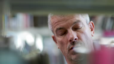 Senior Male looking for a book in library