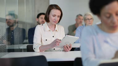 Mature student taking notes on digital tablet in a lecture