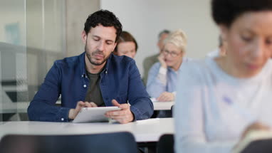 Mature student taking notes on digital tablet in a lecture