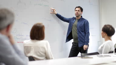 Teacher using white board in adult education course