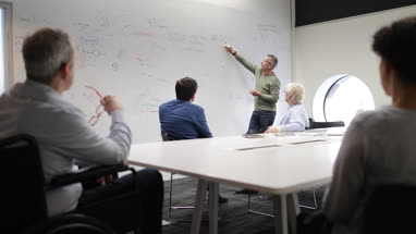 Teacher using white board in adult education course