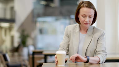 Businesswoman checking smartwatch in cafe
