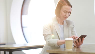Businesswoman waiting in cafe checking smartphone