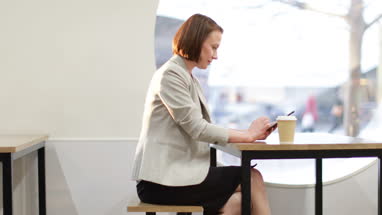 Businesswoman waiting in cafe checking smartphone