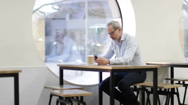 Businessman waiting in cafe checking smartphone