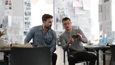 Designers looking at smartphone in creative workspace