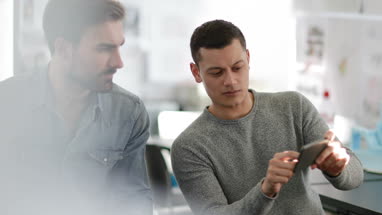 Designers looking at smartphone in creative workspace