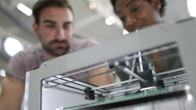 Closeup of colleagues looking at a 3D printer