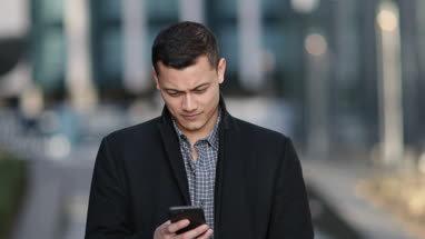 Young adult male checking smartphone in city
