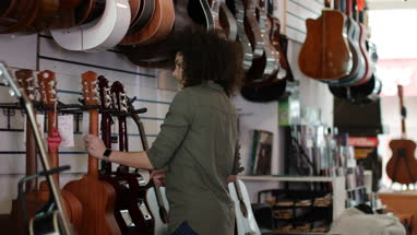 Young adult female looking at acoustic guitars in a store