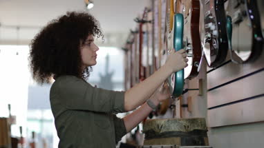 Young adult female looking at electric guitars in a store