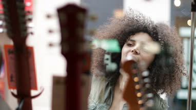 Young adult female window shopping acoustic guitars 