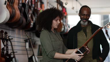 Small business owner helping customer in a guitar store