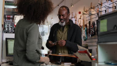 Senior male paying in a guitar store with credit card