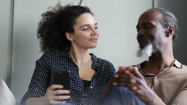 Daughter looking at photos on smartphone with Father at home