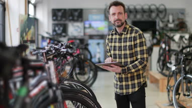 Portrait of a small business owner using digital tablet in a cycle store