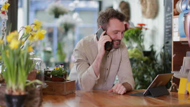 Small business owner using digital tablet and smartphone in a florist
