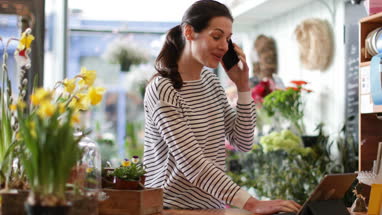Small business owner using digital tablet and smartphone in a florist