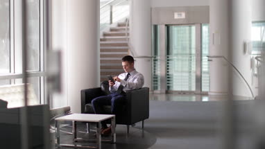 Businessman waiting in office reception using smartphone