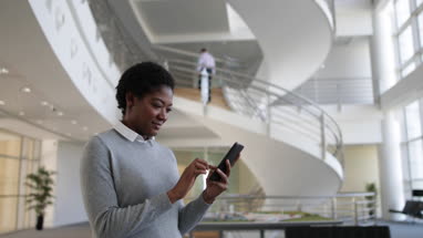 African American using smartphone in modern office