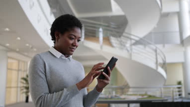 African American using smartphone in modern office