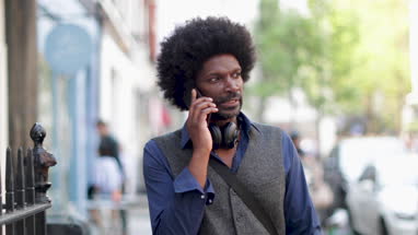 African American male walking and on on smartphone in city