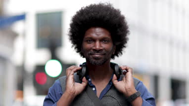 Portrait of African American male outdoors in city listening to headphones