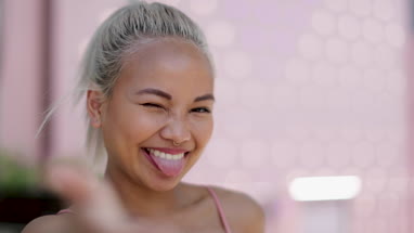 Young adult female taking selfie with pink background