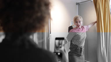 Young adult female trying on clothes in a vintage store with friend