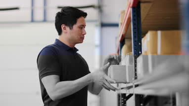 Male picking up box from shelf in distribution warehouse