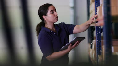 Female working in distribution warehouse with digital tablet