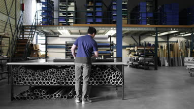 Male measuring fabric in a manufacturing warehouse