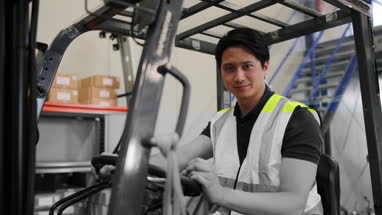 Portrait of male working in distribution warehouse on a forklift 