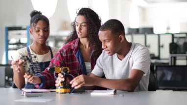 High school students working on a robotic arm in class