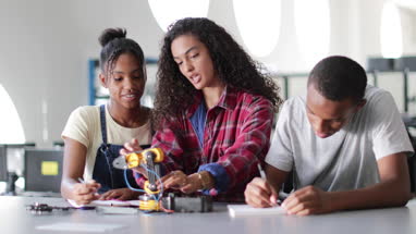 High school students working on a robotic arm in class