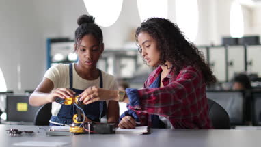High school students working on a robotic arm in class