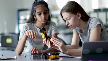 High school students working on a robotic arm in class