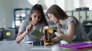 High school students working on a robotic arm in class