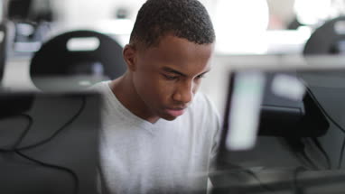 Closeup teenage boy using a computer in class