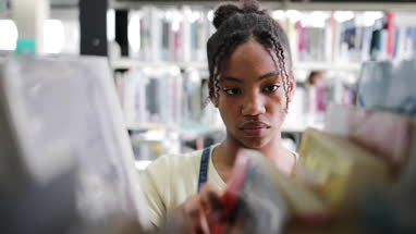 Teen african american girl choosing book in library