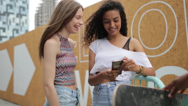 Teenagers socialising outdoors in city looking at smartphone