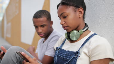 Teenagers socialising outdoors in city looking at smartphone
