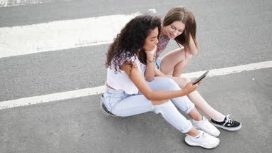 Female teenage friends looking at smartphone